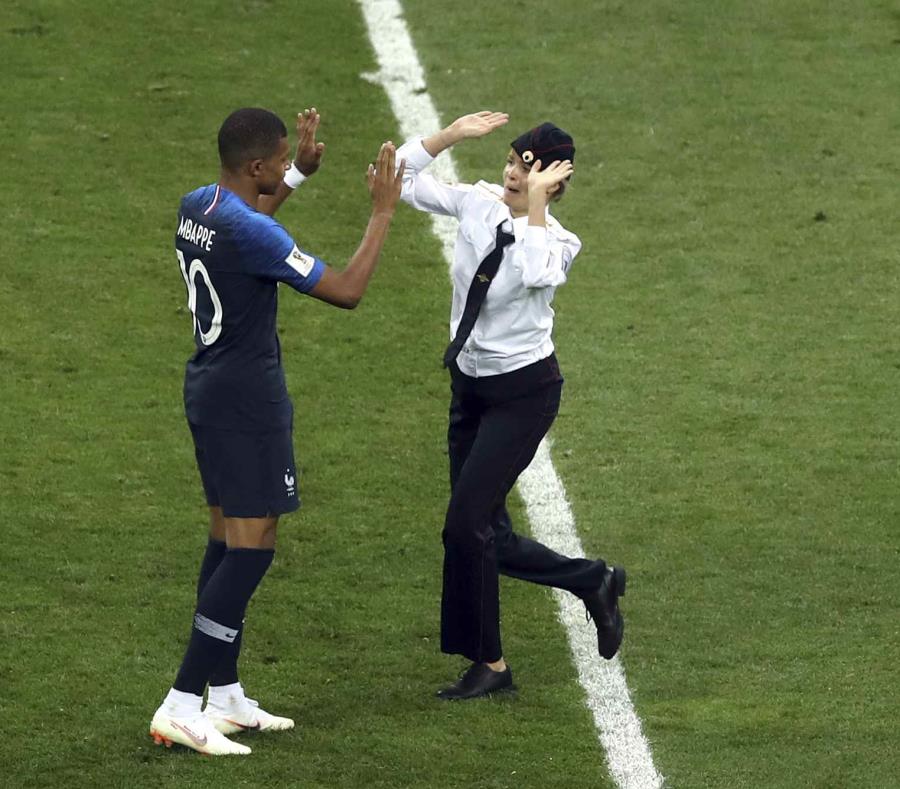 Una mujer que irrumpió en la cancha se acerca al delantero francés Kylian Mbappé durante la final del Mundial en el estadio Luzhniki de Moscú, el domingo 15 de julio de 2018. (AP) (semisquare-x3)