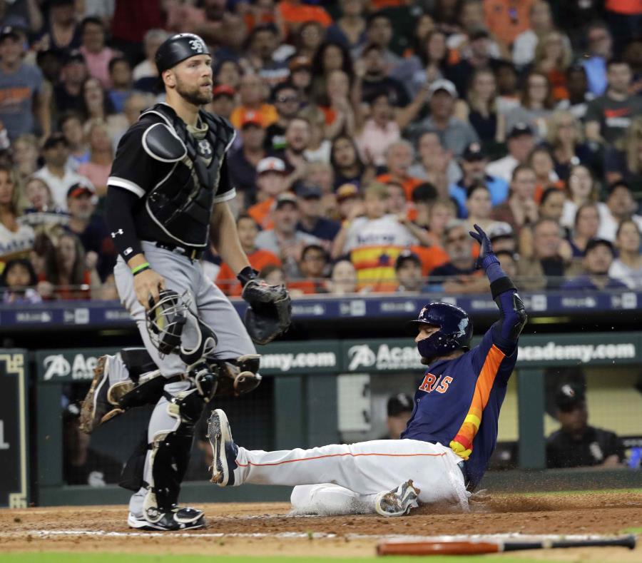 El jugador de los Astros de Houston Yuli Gurriel se barre para anotar tras un toque de sacrificio del venezolano Marwin González durante el séptimo inning de un juego de béisbol el domingo 8 de julio de 2018 en Houston