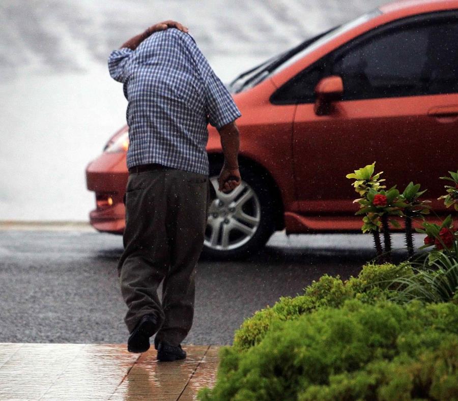 Un hombre se cubre con su camisa para evitar mojarse con la lluvia. (GFR Media) (semisquare-x3)