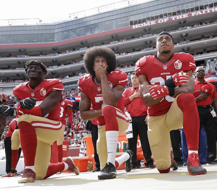 Colin Kaepernick (centro), de los 49ers de San Francisco, se arrodilla con otros compañeros durante la interpretación del himno nacional. (AP) (semisquare-x3)