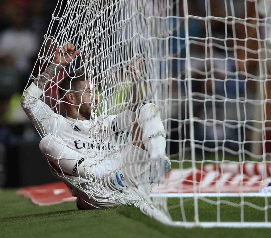 Sergio Ramos, del Real Madrid, parece acostarse en la malla de la portería durante un partido. (AP) (semisquare-x3)