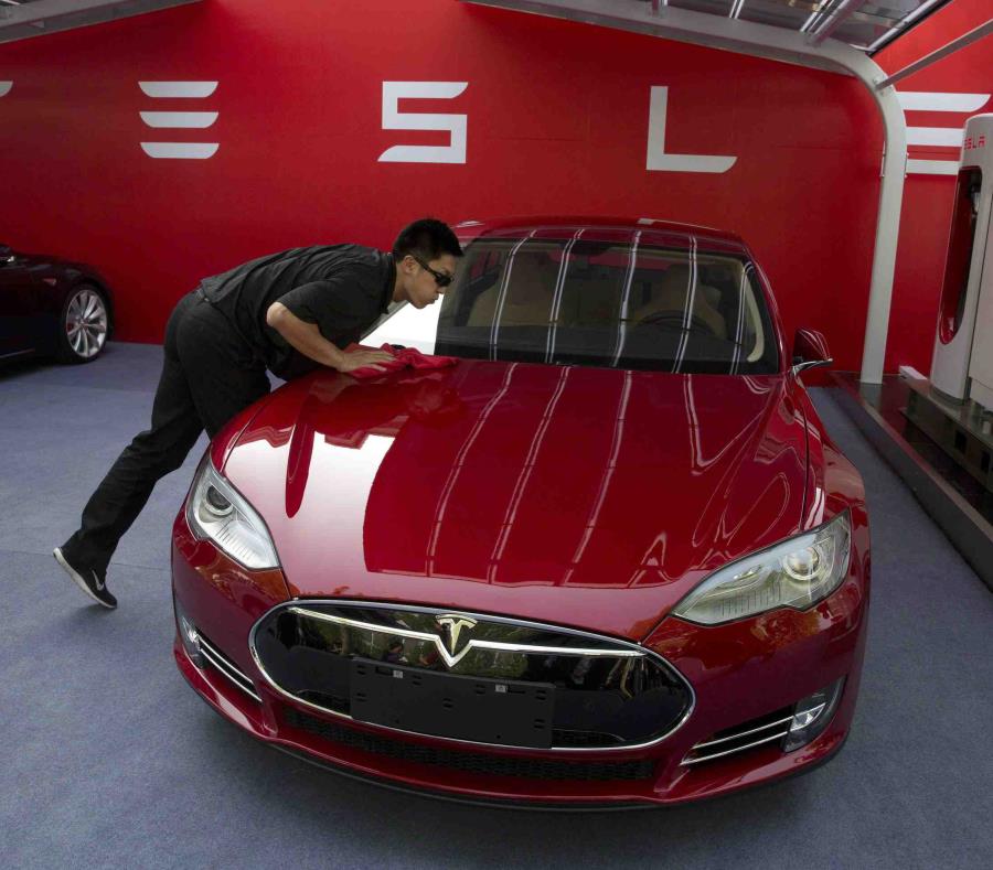 Un trabajador limpiando un sedán Tesla Model S. (semisquare-x3)