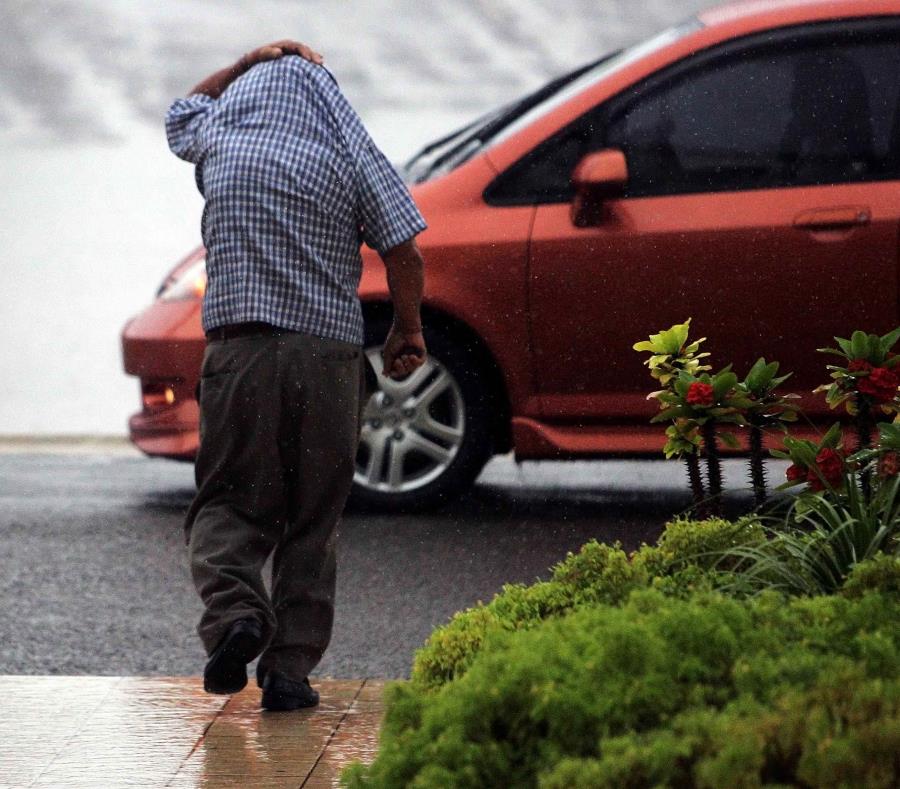 Un hombre se cubre con su camisa de la lluvia. (GFR Media) (semisquare-x3)