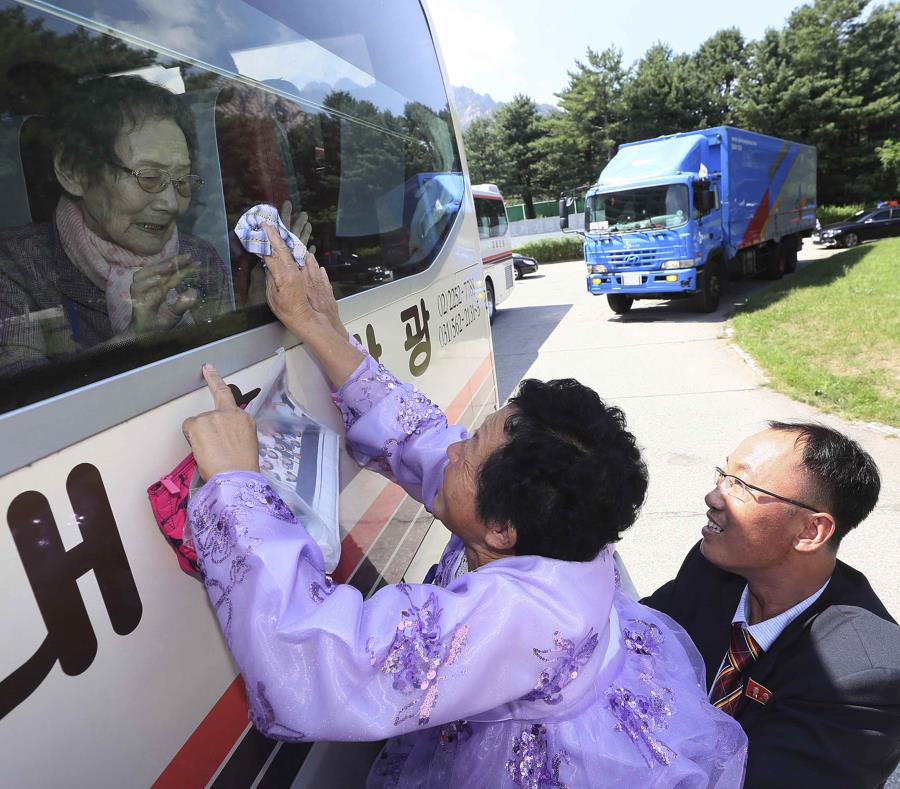 La norcoreana Kim Kyong Sil toca la ventana de un autobús para depedirse de su madre surcoreana, Han Shin-ja, de 99 años, tras una reunión familiar en el balneario de Diamond Mountain, en Corea del Norte. (AP) (semisquare-x3)