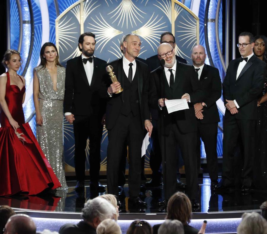 En esta imagen difundida por NBC, Joel Fields, en el centro, y Joe Weinberg, a su lado, reciben el Globo de Oro a la mejor serie de drama por