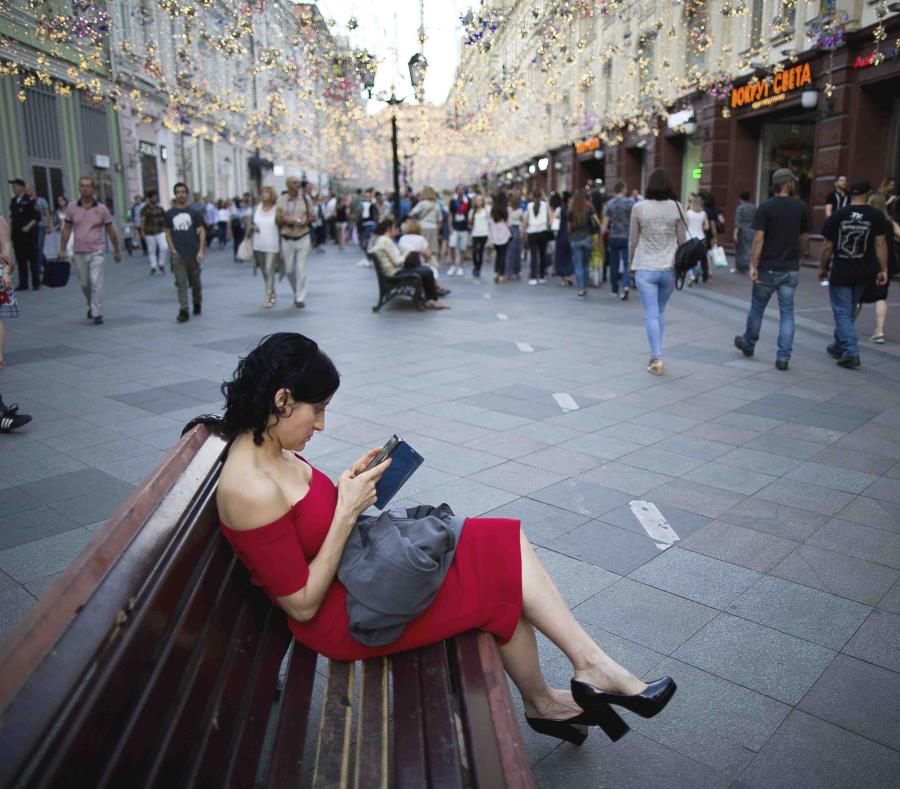 Una mujer observa su teléfono celular en la calle Nikolskaya, favorita de los fanáticos del fútbol, cerca de la Plaza Roja. (AP) (semisquare-x3)