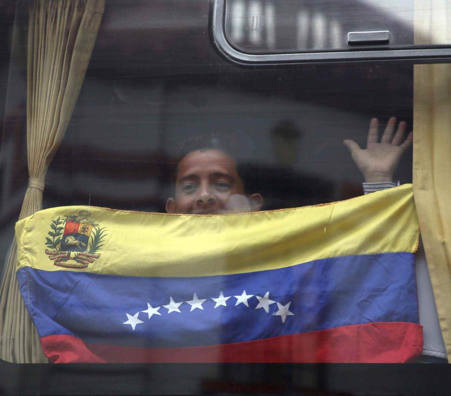 Un migrante venezolano con la bandera nacional saluda desde un bus que lo llevará al aeropuerto de Lima para el regreso a su país (semisquare-x3)