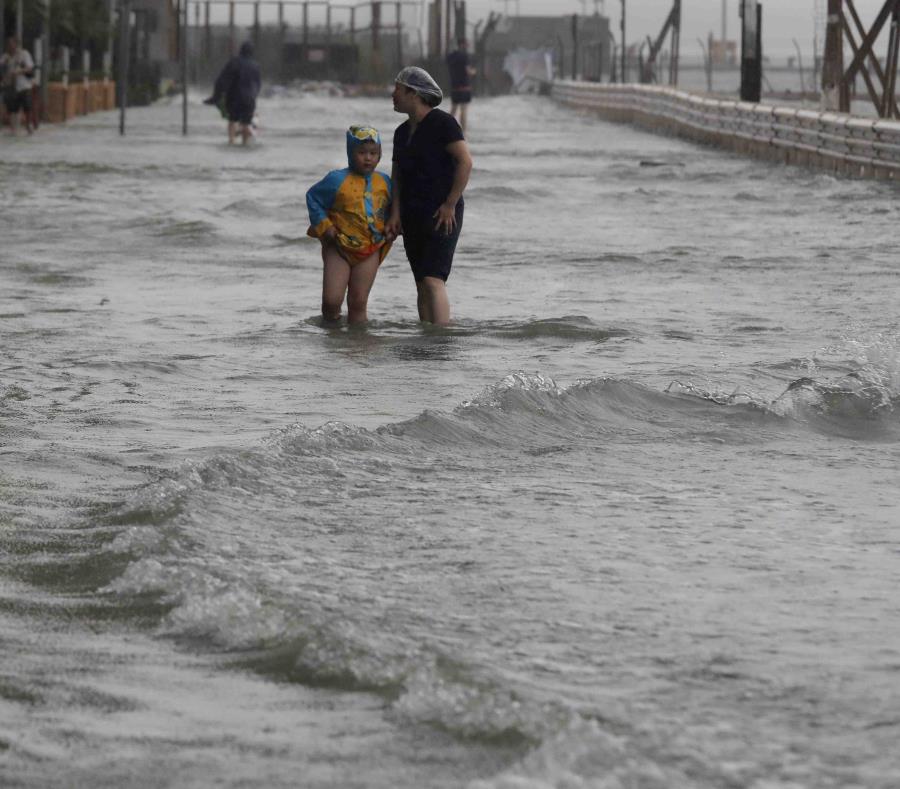 Unas personas caminan a través de una inundación causada por el tifón Mangkhut en Hong Kong, el domingo 16 de septiembre de 2018. (AP Foto/Vincent Yu) (semisquare-x3)