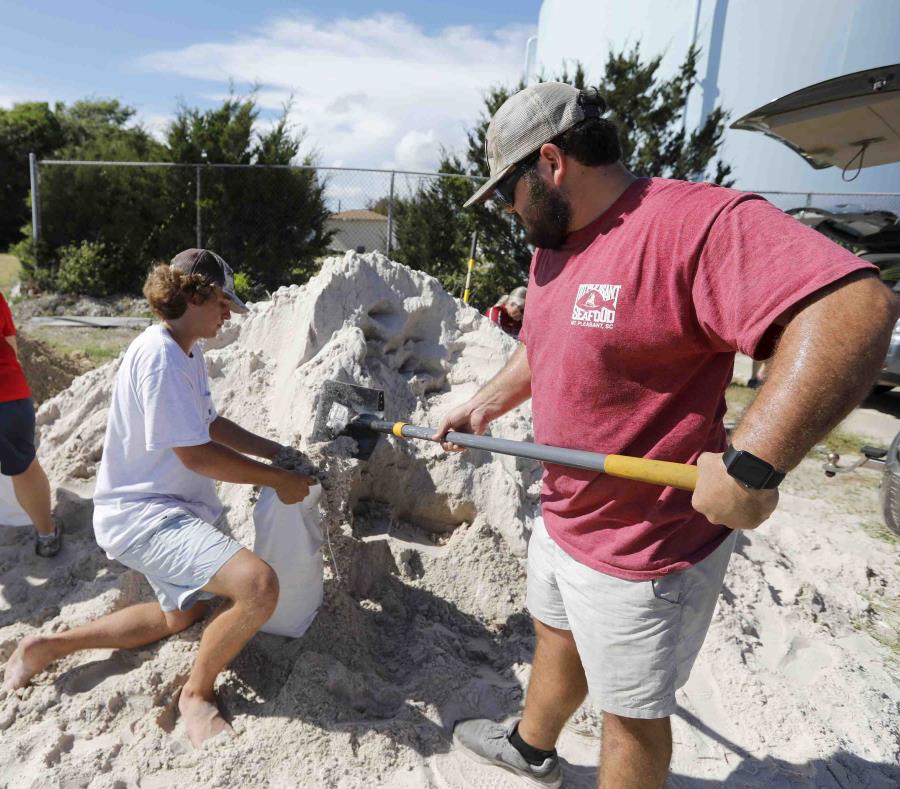 Walker Townsend, de Isle of Palms, en Carolina del Sur, llena un saco de arena que sostiene Dalton Trout, en un estacionamiento municipal donde se reparte arena de forma gratuita dentro de los preparativos para la llegada del huracán Florence a la región. (semisquare-x3)