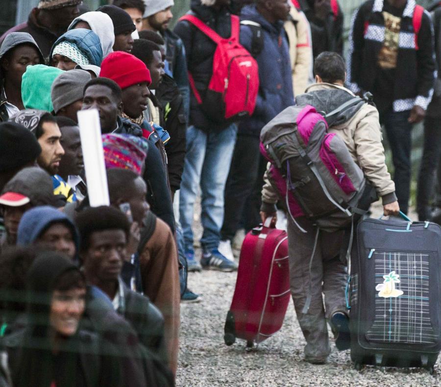Varios migrantes esperan una cola en el centro de recepción de corta estancia (semisquare-x3)