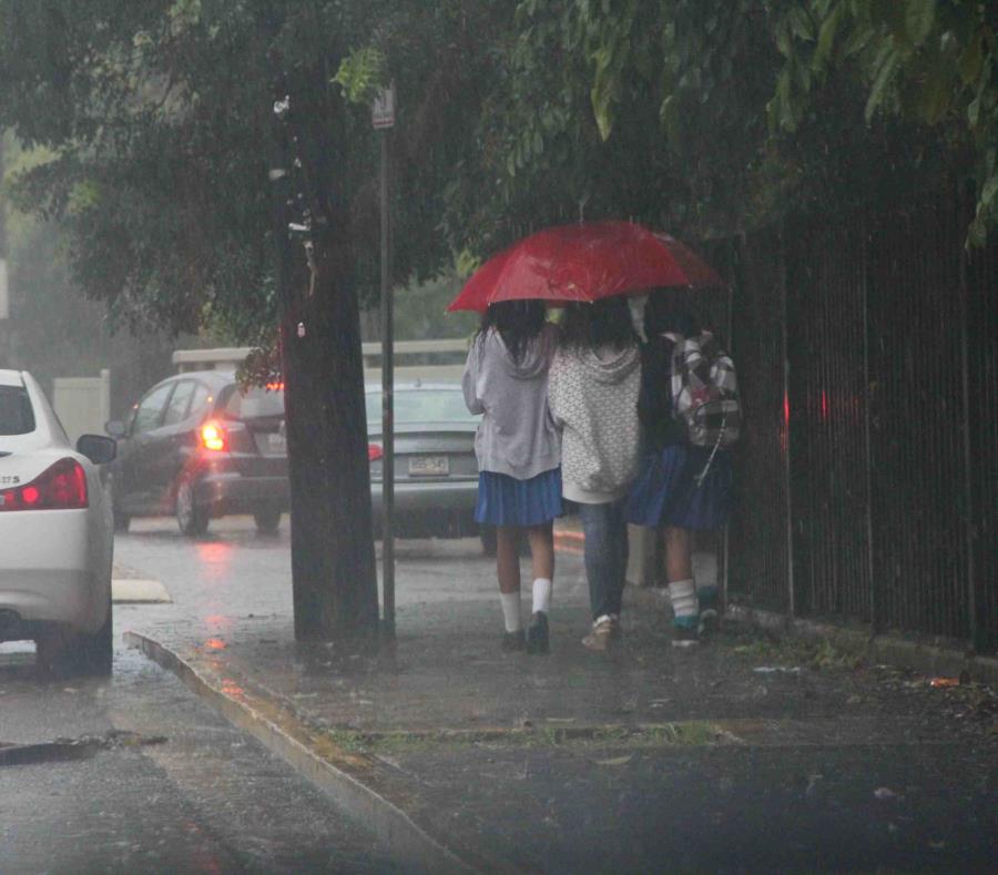 Unas estudiantes se escudan de la lluvia con una sombrilla. (GFR Media) (semisquare-x3)