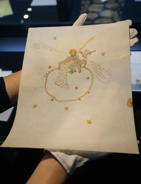 Un empleado de la casa subastadora Artcurial muestra una acuarela de Antoine de Saint-Exupery, realizada alrededor de 1942, en París, 15 de junio de 2018. (AP) (vertical-x1)